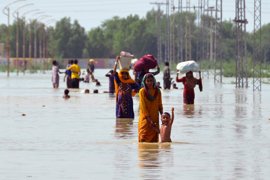 People wade through knee-high flood waters.