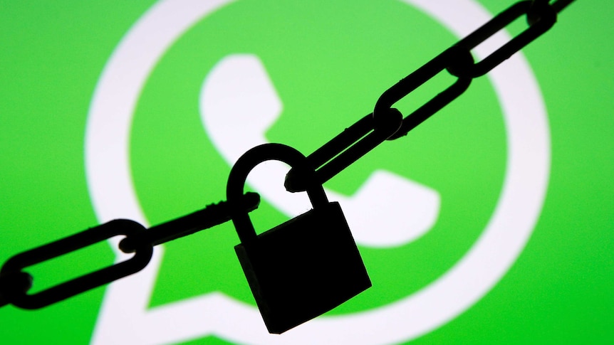 A photo illustration shows a chain and a padlock in front of a displayed Whatsapp logo.