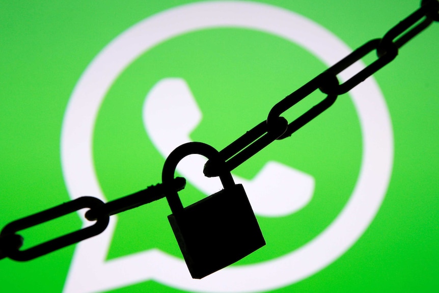 A photo illustration shows a chain and a padlock in front of a displayed Whatsapp logo.