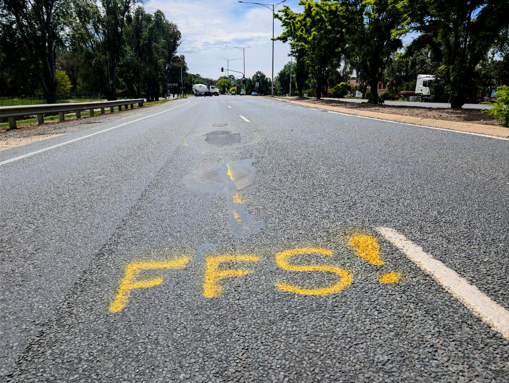 Spray painted Labor approved sign on road near pothole