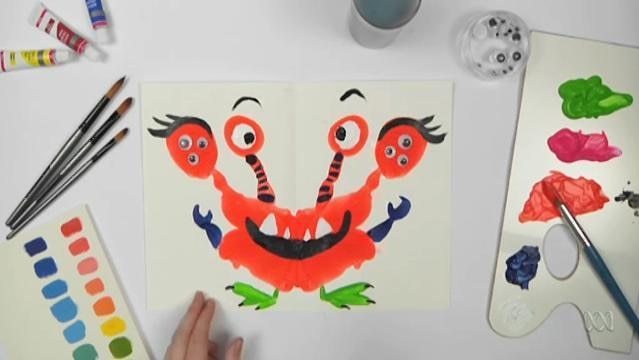 Hand points to painting of smiling monster with four heads