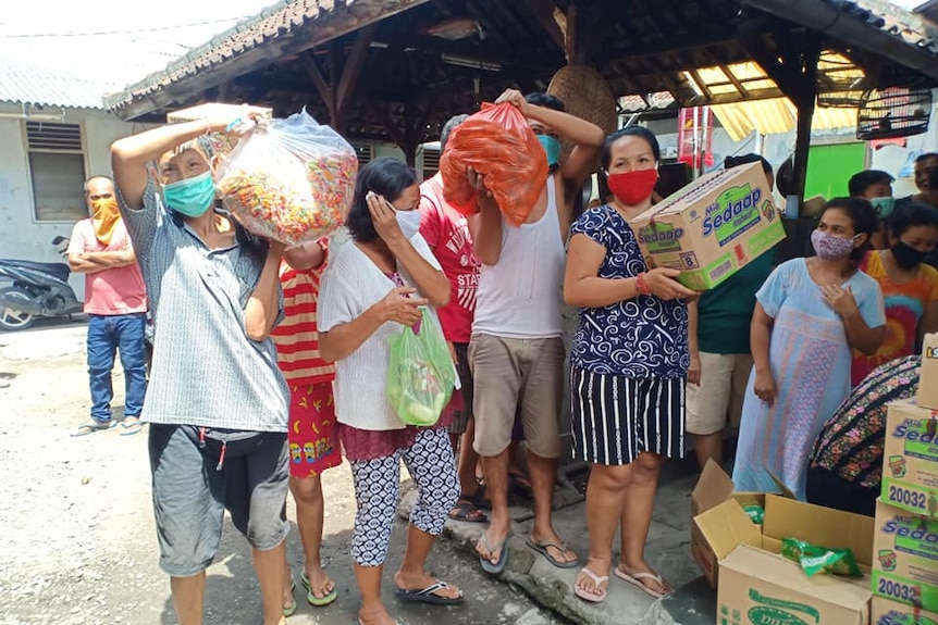 People lining up and carrying bags and boxes of food.