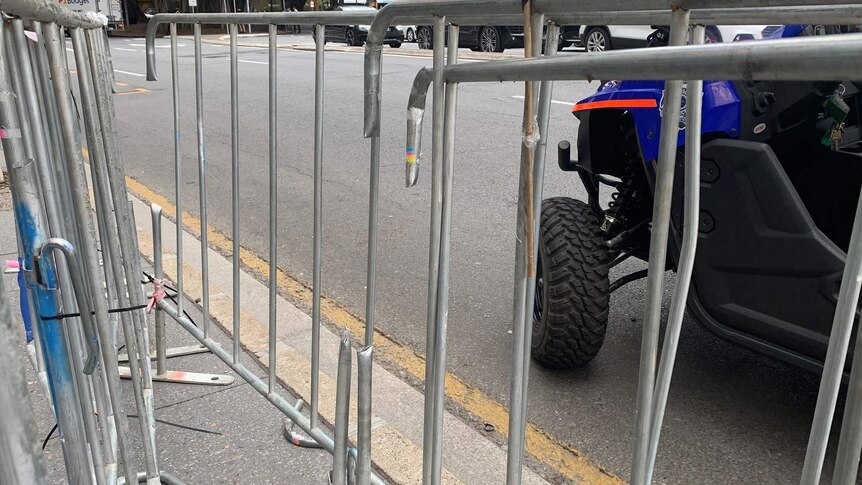 Temporary fencing on the side of a road has paling missing from where police used bolt cutters to release protesters.