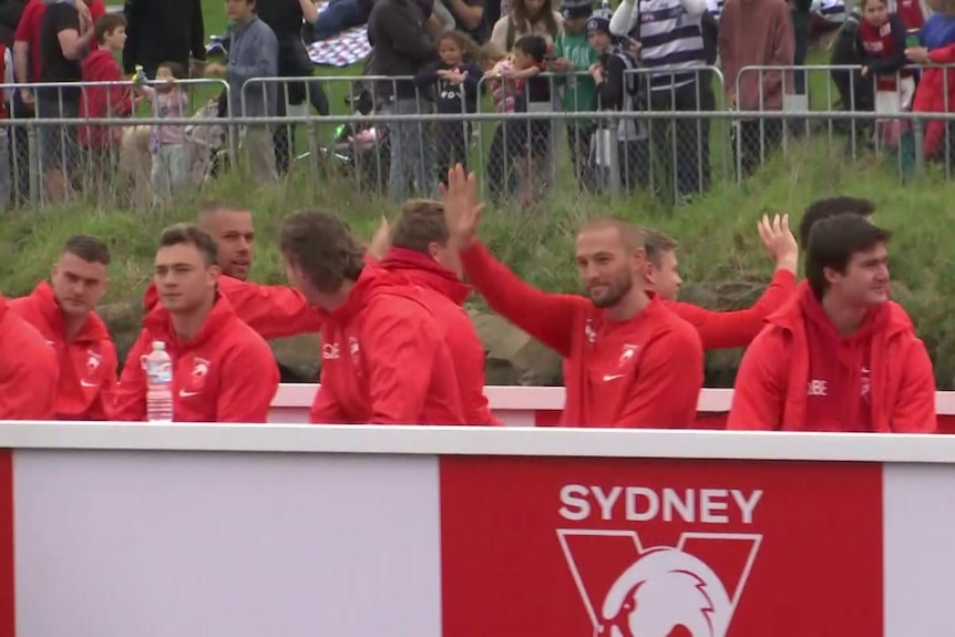 Sydney Swans players wave to fans from a barge on the Yarra River during the 2022 grand final parade.