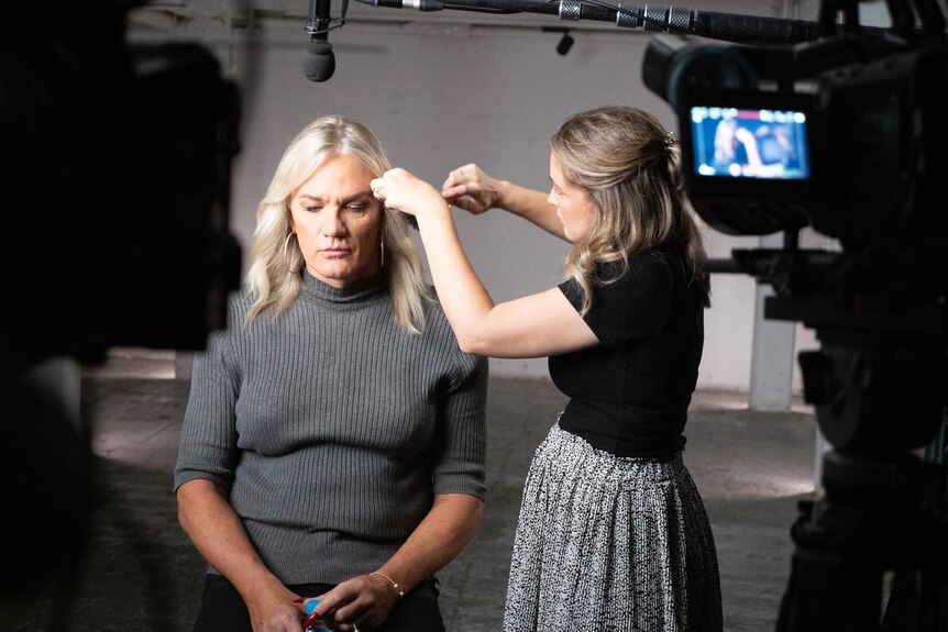 Danielle Laidley sits in a studio, a makeup artist is doing touch up as Danielle prepares for the camera.