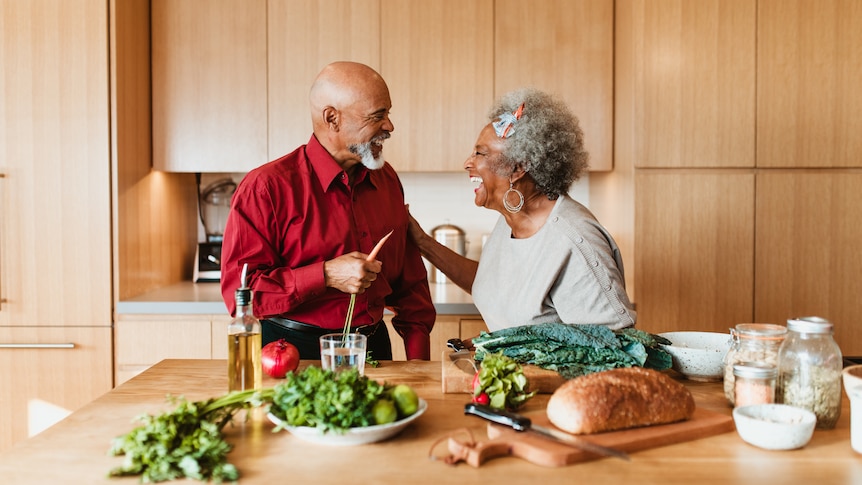 A smiling senior couple preparing a vegan meal in their kitchen at home.