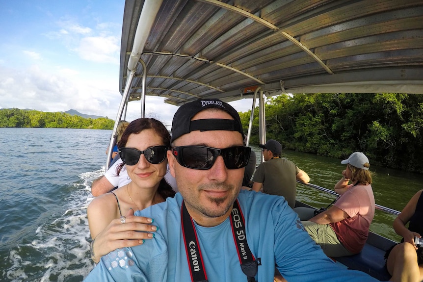 A man and woman sit in a boat on a river.