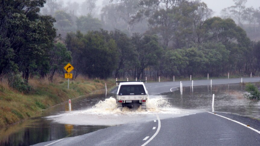 A vehicle drives along a flood-affected road at Avoca in Tasmania's NE.