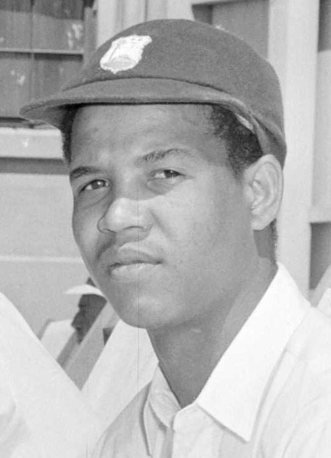A black and white photo of a young man wearing a cricket cap