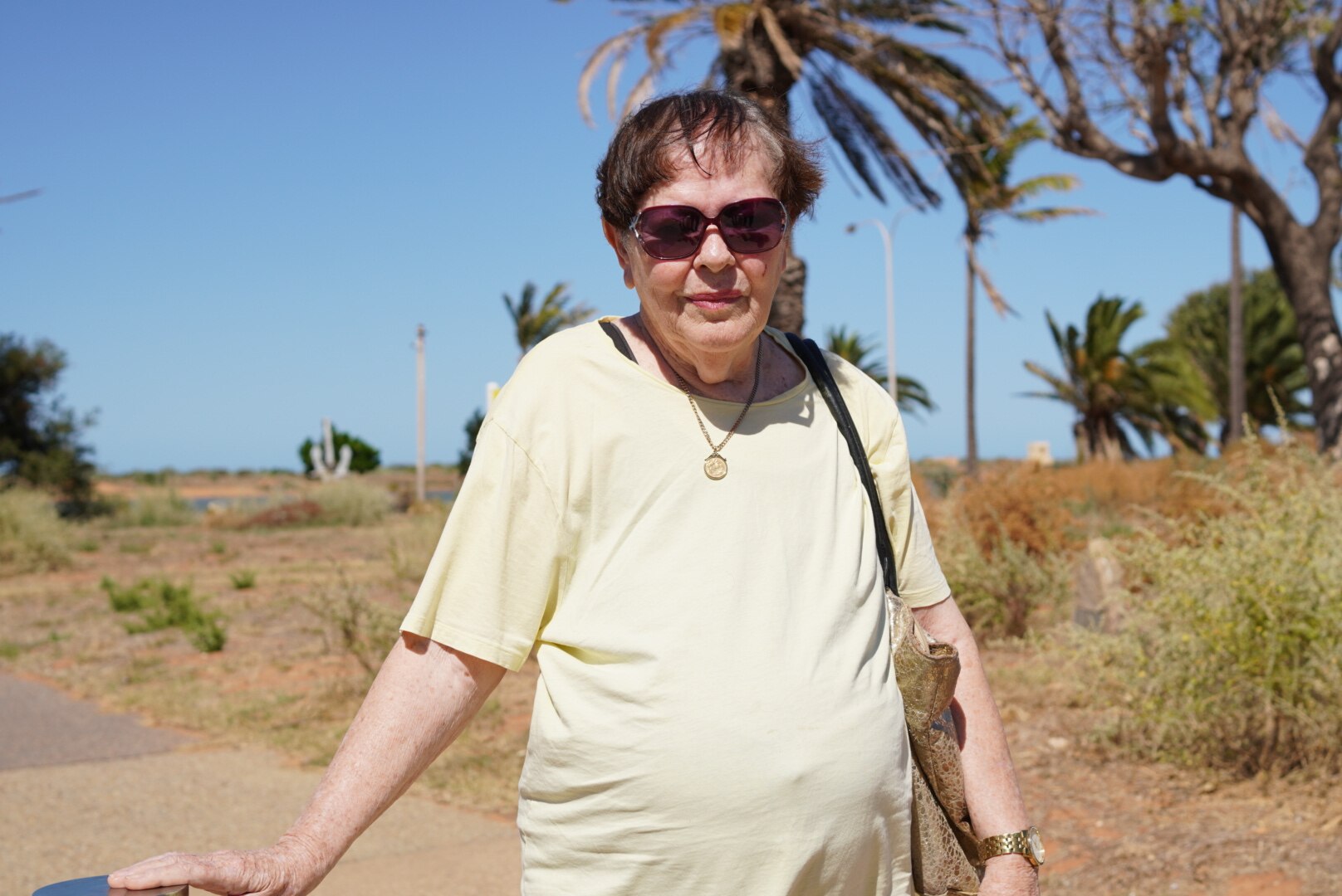 A photo of Jenny Walsh wearing sunglasses with trees in the background.