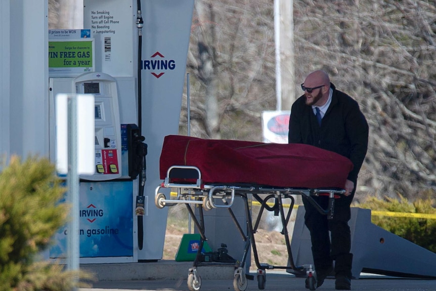 A man pushes a stretcher with a body bag on top