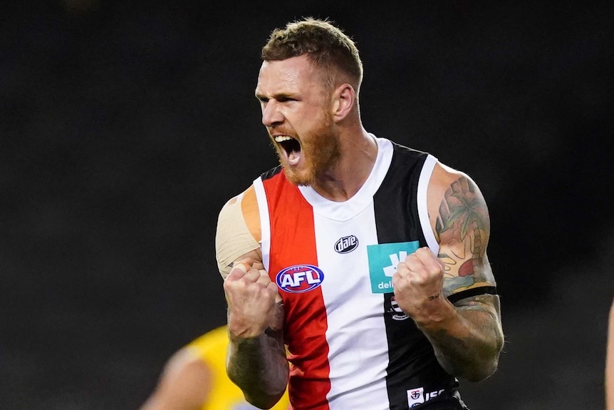 A St Kilda AFL player pumps both fists and screams out as he celebrates a goal against Richmond.