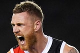 A St Kilda AFL player pumps both fists and screams out as he celebrates a goal against Richmond.