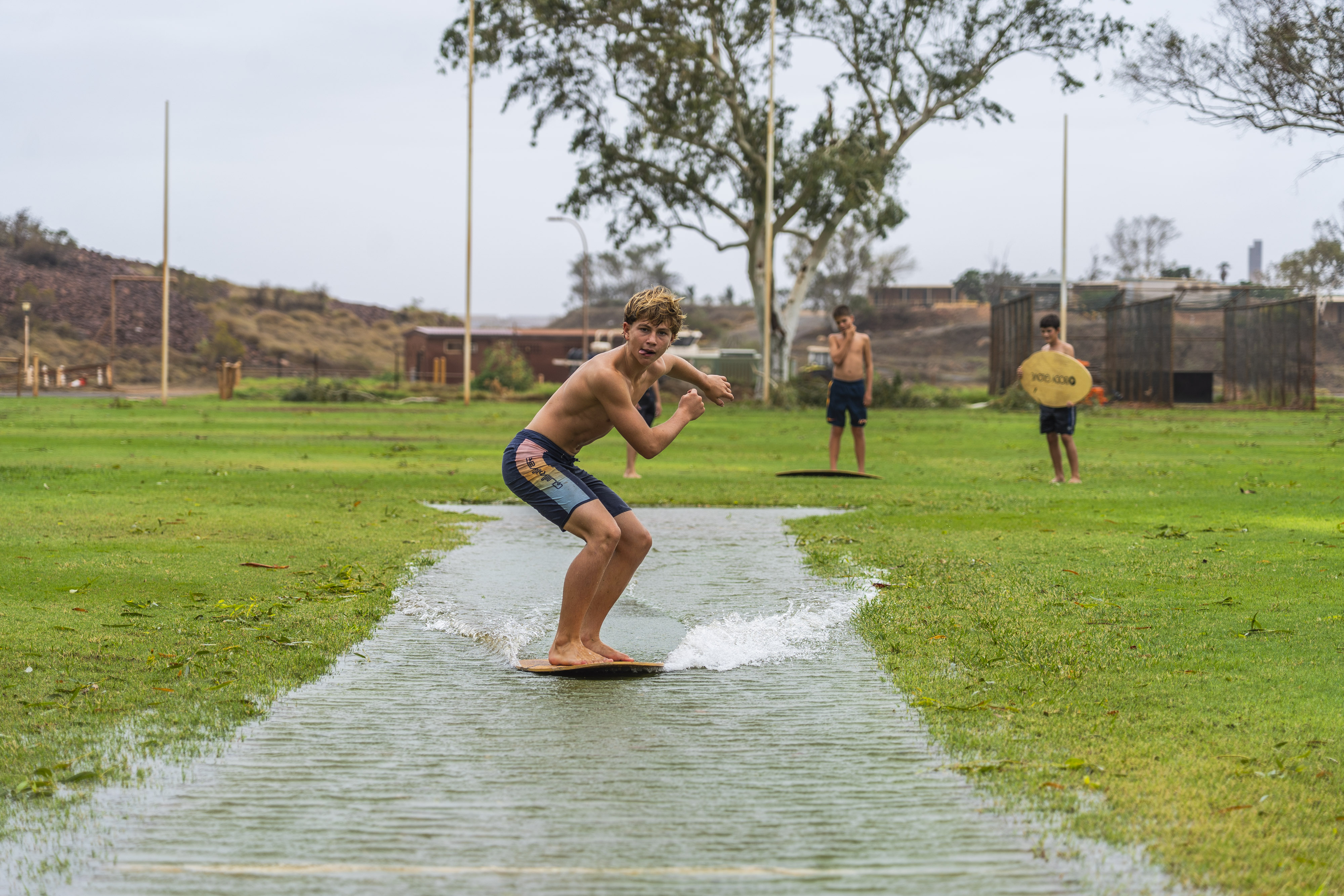 Niños en el agua con tablas de wakeboard en un campo de cricket