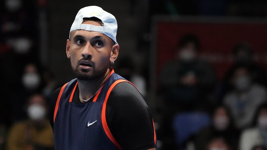 Australia's Nick Kyrgios looks across court while wearing a backwards-facing cap during a match.