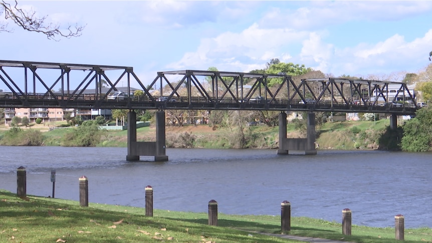 A bridge over a waterway with grassy banks.