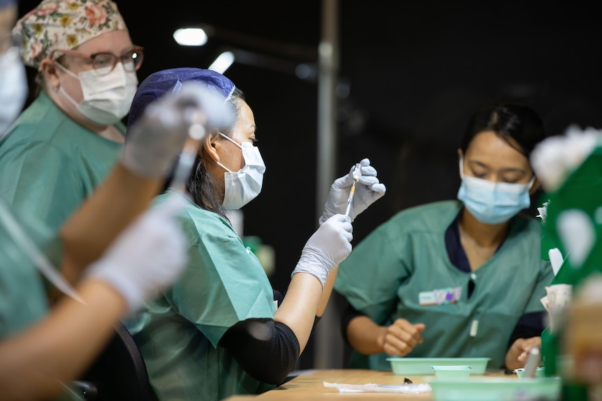 Nurses pulling vaccines into syringes.