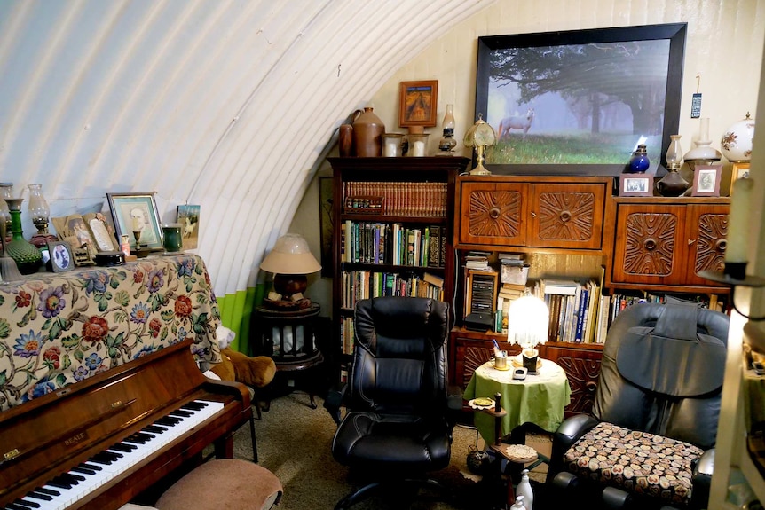 A piano and bookshelves in a curved walled bunker
