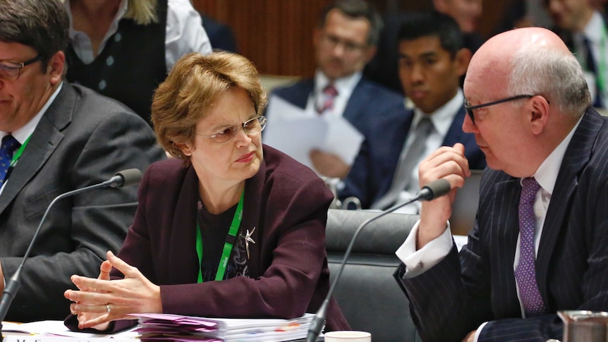 DFAT Secretary Frances Adamson speaks to Attorney-General George Brandis at the DFAT Senate Committee meeting.