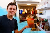Pat Wright holds leftover spaghetti in front of an open fridge in story about storage tips for meals, dairy, vegetables, fruit.