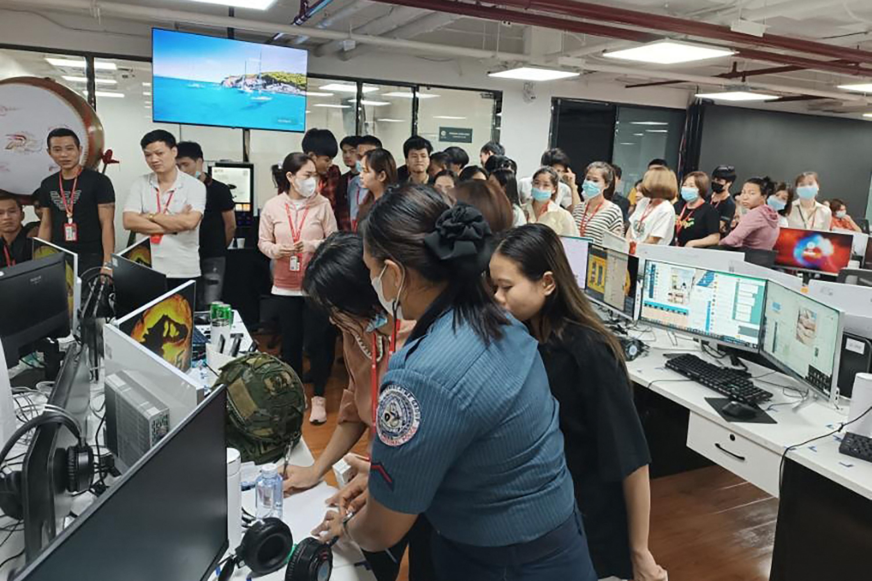 A group of people in face masks in an office with people in police uniforms in the foreground