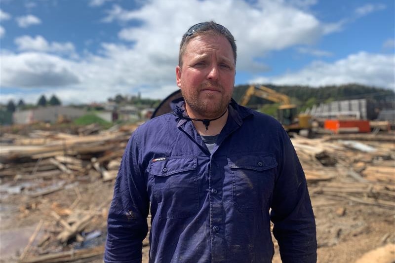 A man stands in front of a timber yard