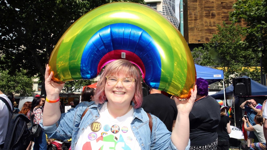 Amalie O'Hara holds a rainbow balloon above her head at the yes event in Melbourne