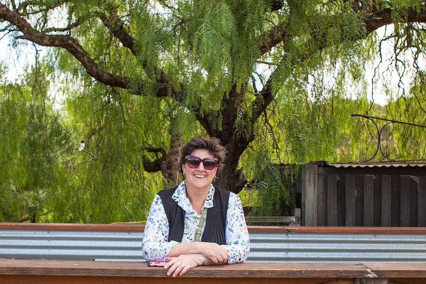 Woman stands behind a rail under a big peppcorn tree Collingwood Children's Farm, Melbourne