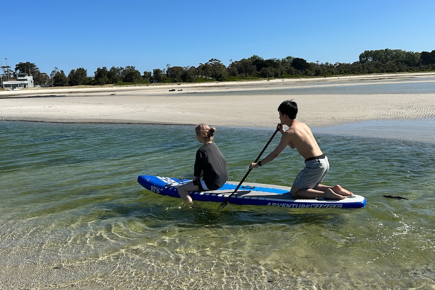 Young people on a stand-up paddleboard.