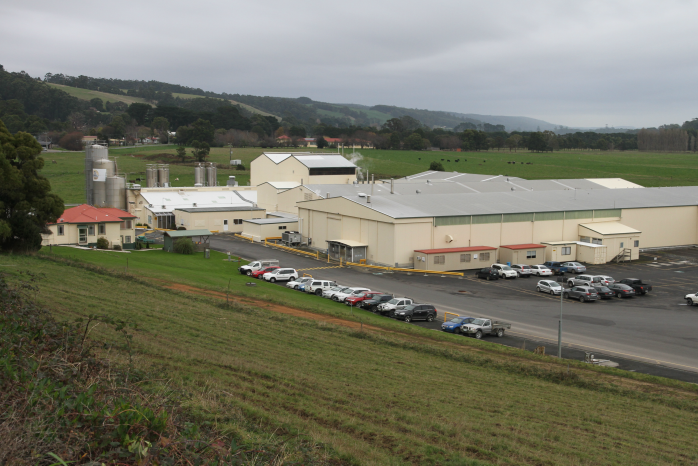 A factory and carpark surrounded by paddocks.