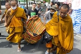 Buddhist monks carry an injured Red Shirt anti-government protester.