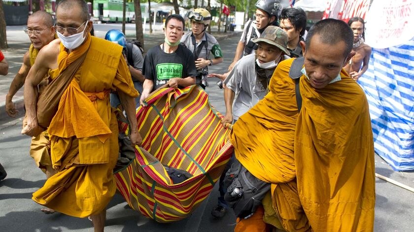 Buddhist monks carry an injured Red Shirt anti-government protester.