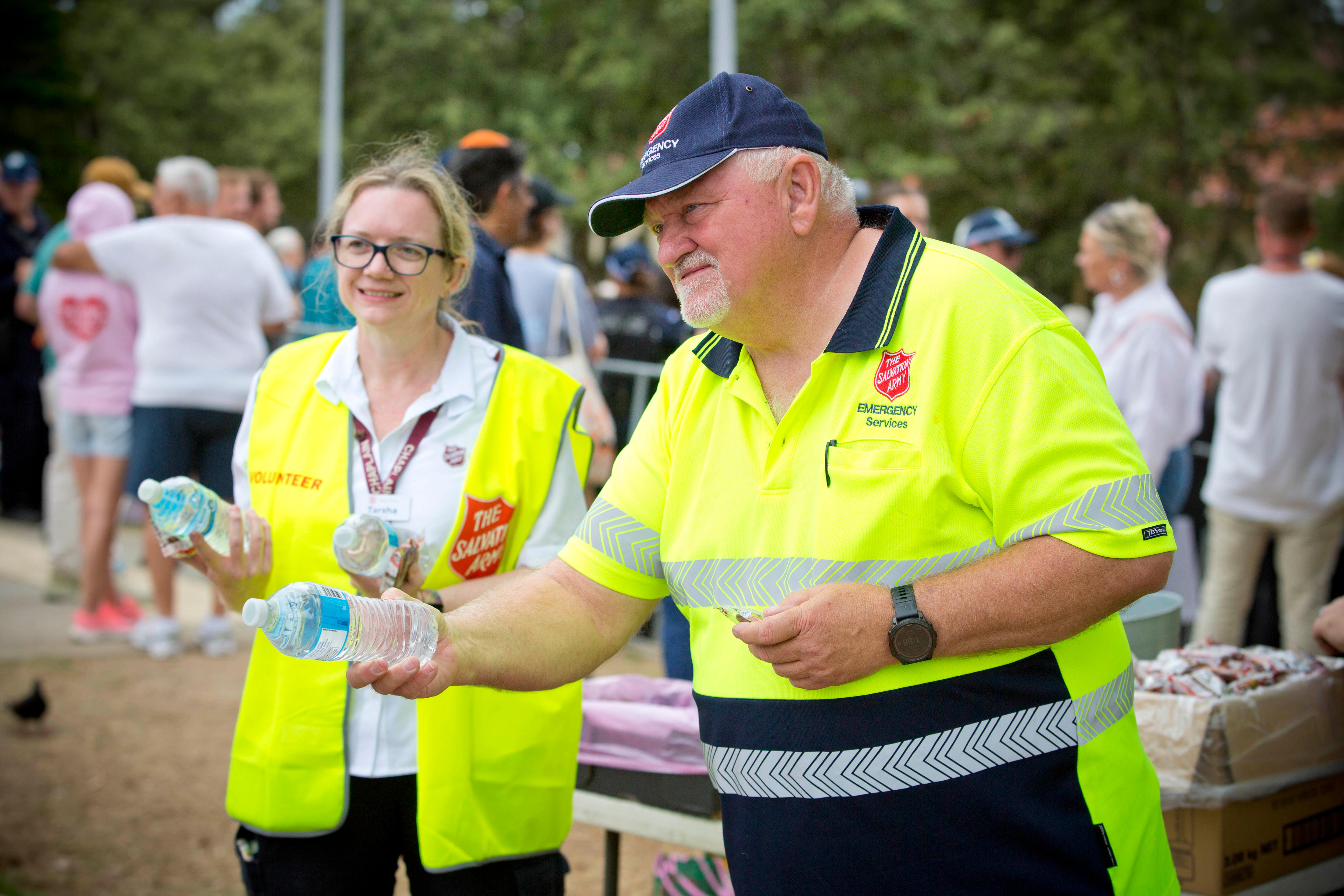 Um homem barbudo com uma camisa do Exército da Salvação oferece uma garrafa de água