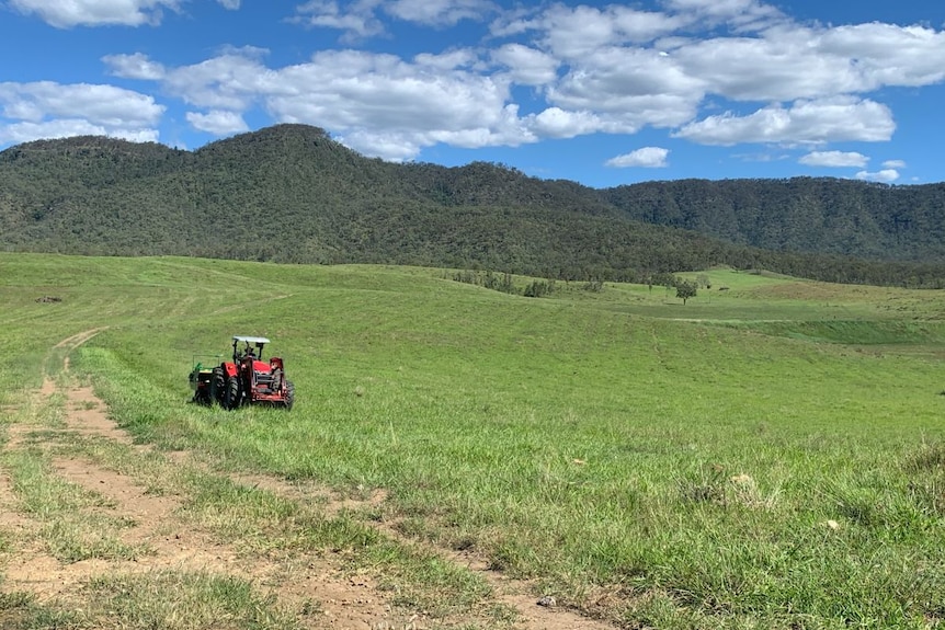 A seeder in a native pasture with hills in the background.