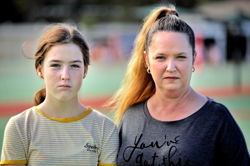 A woman and 12-year-old daughter stand on netball courts.