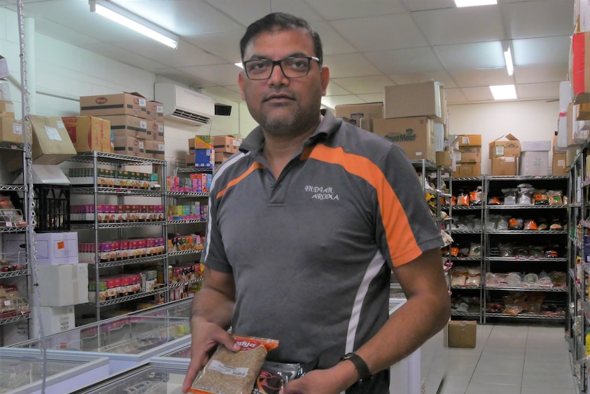grocer in his store holding spice packets