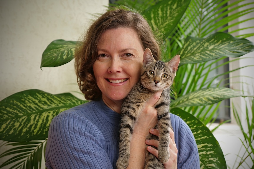 Author Dianne Salvador holds a young tabby cat up to her face.