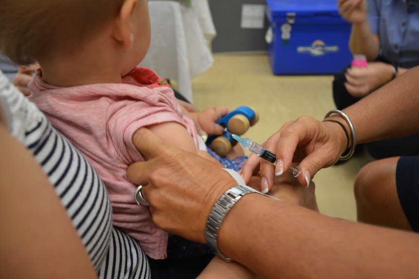 A nurse prepares to give a needle to a baby