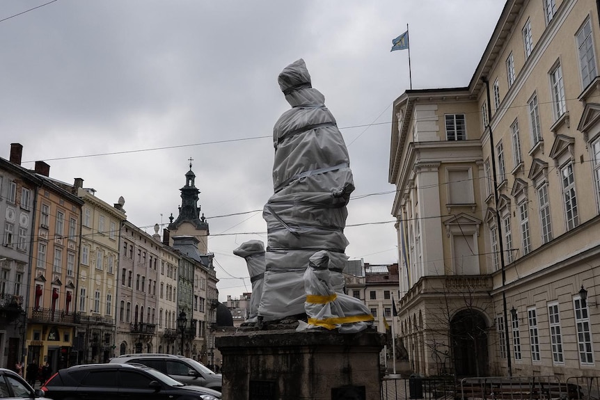 a statue on a street in Lviv is wrapped in plastic and taped up