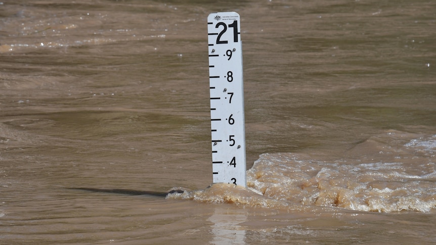 Flood marker with brown water flowing past