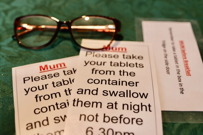 laminated notes to remember to take tablets and a pair of glasses