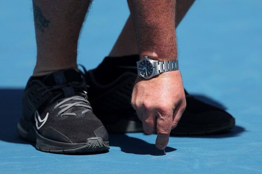 The court surface at the Australian Open is inspected.
