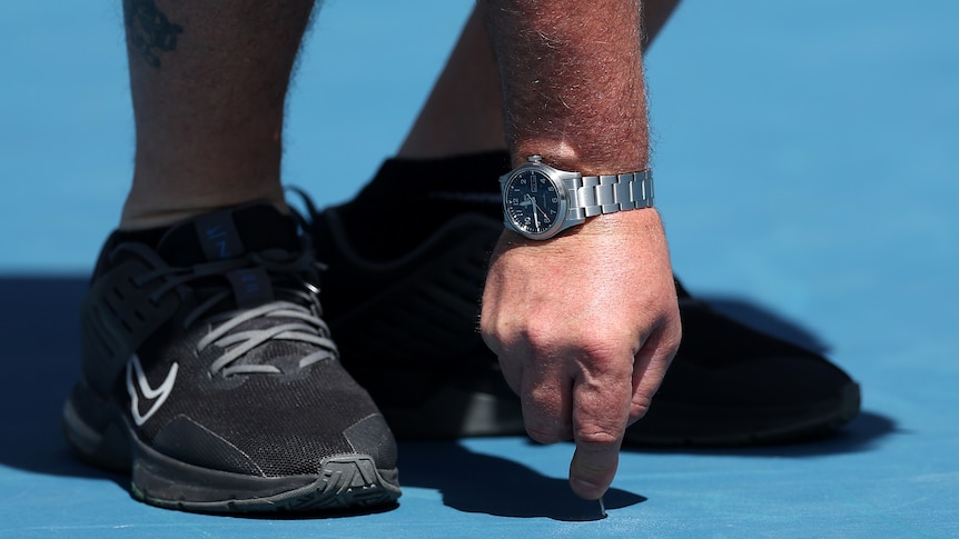 The court surface at the Australian Open is inspected.