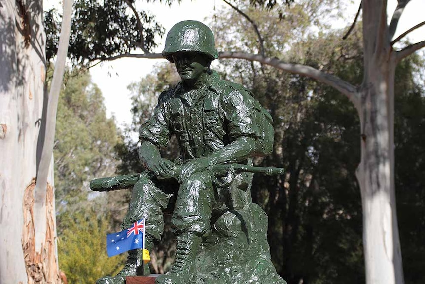 Green painted statue of a soldier sitting
