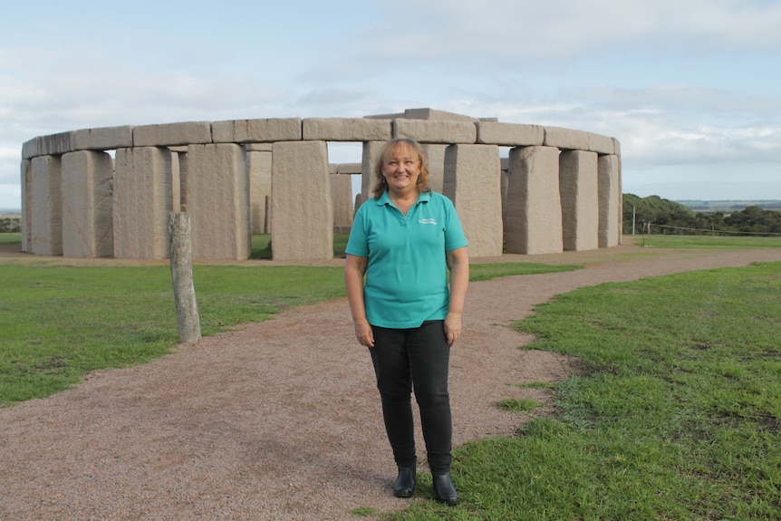A woman stands in front of Stonehenge replica. 
