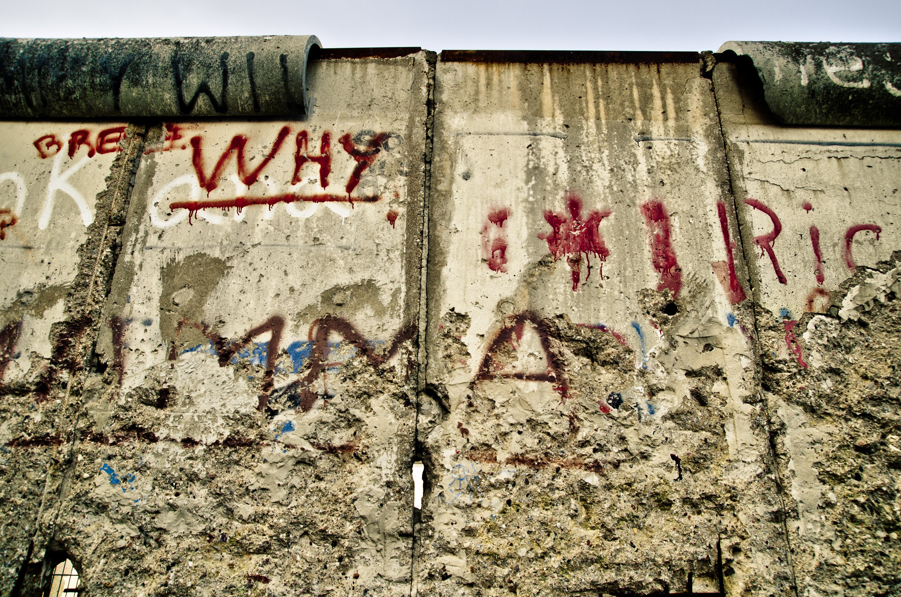 Concrete Berlin Wall in a state of decay with word "WHY" in red paint