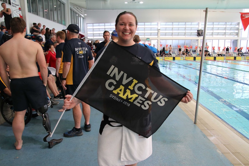 Vanessa Broughill holds an Invictus Games flag.