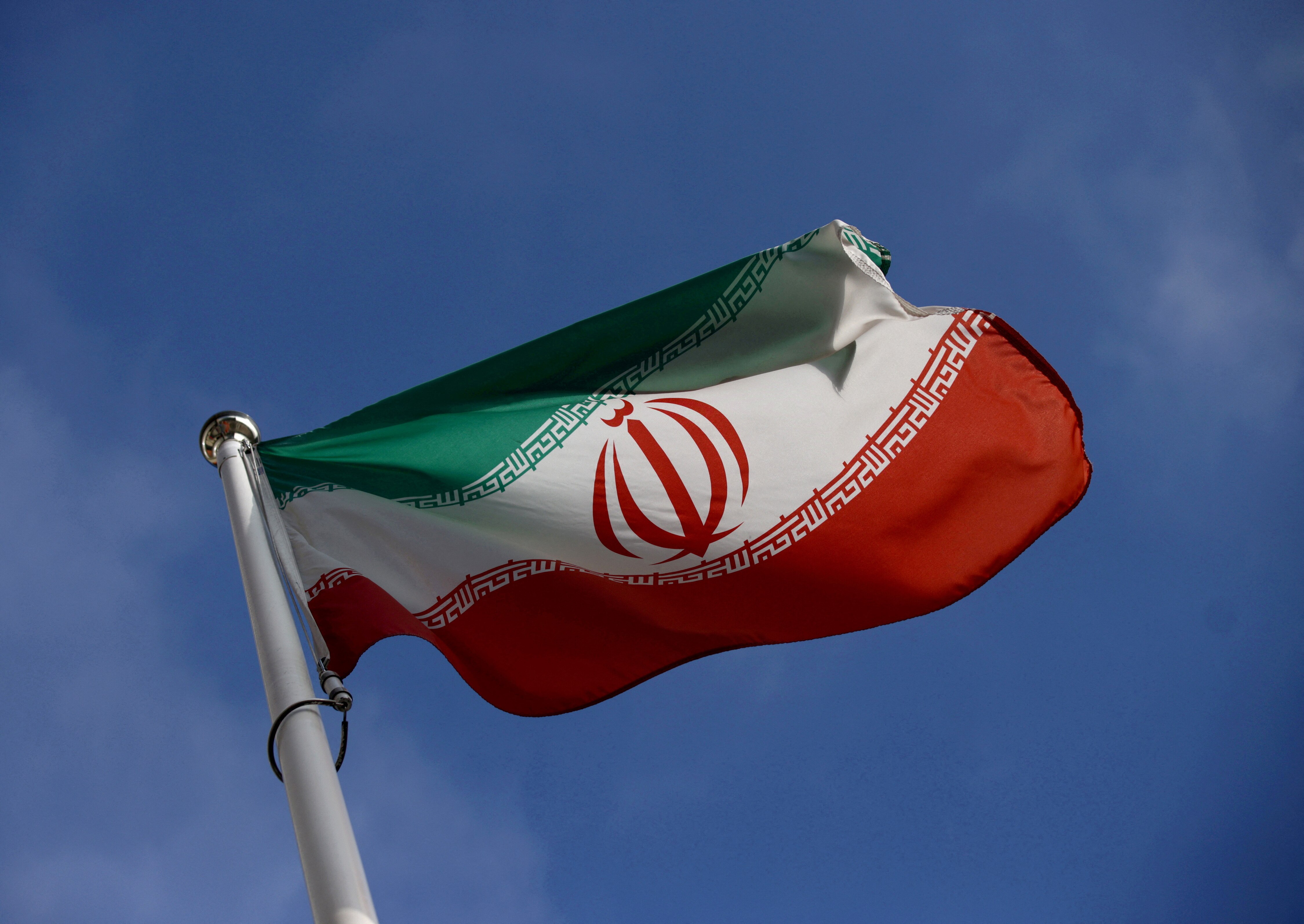 The green white and red Iranian flag on a flag pole.