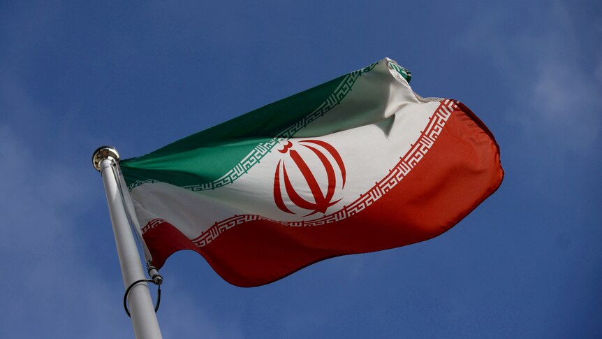 The green white and red Iranian flag on a flag pole. 