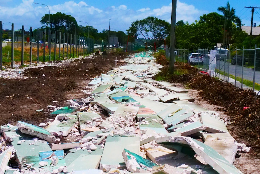 A long pile of rubble lies between two fences.